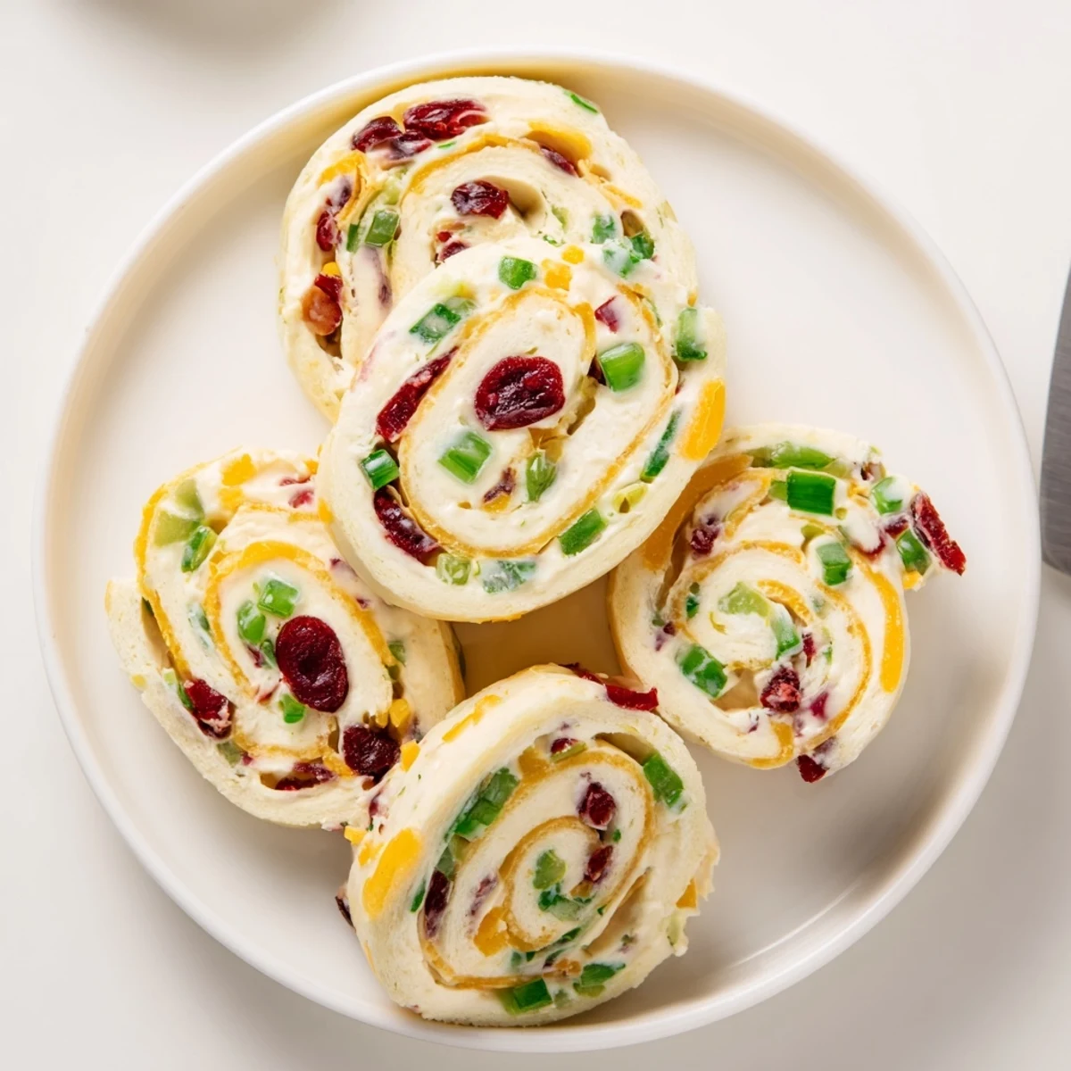 Colorful tortilla rolls filled with tangy cranberries and spicy jalapeños, perfect for entertaining.  