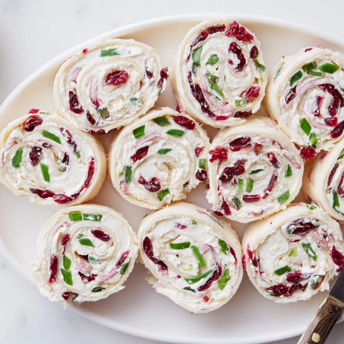 Vibrant cranberry jalapeño cream cheese pinwheels arranged neatly on a festive platter.