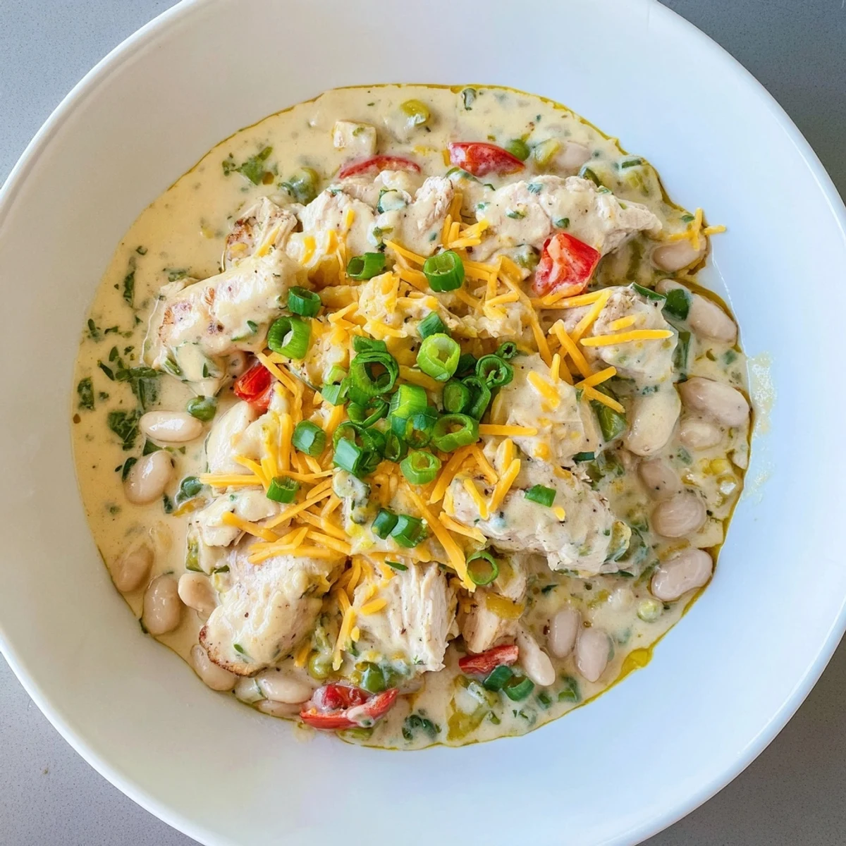 Savory bowl of Creamy White Chicken Chili with beans, garnished with fresh cilantro and lime wedges.
