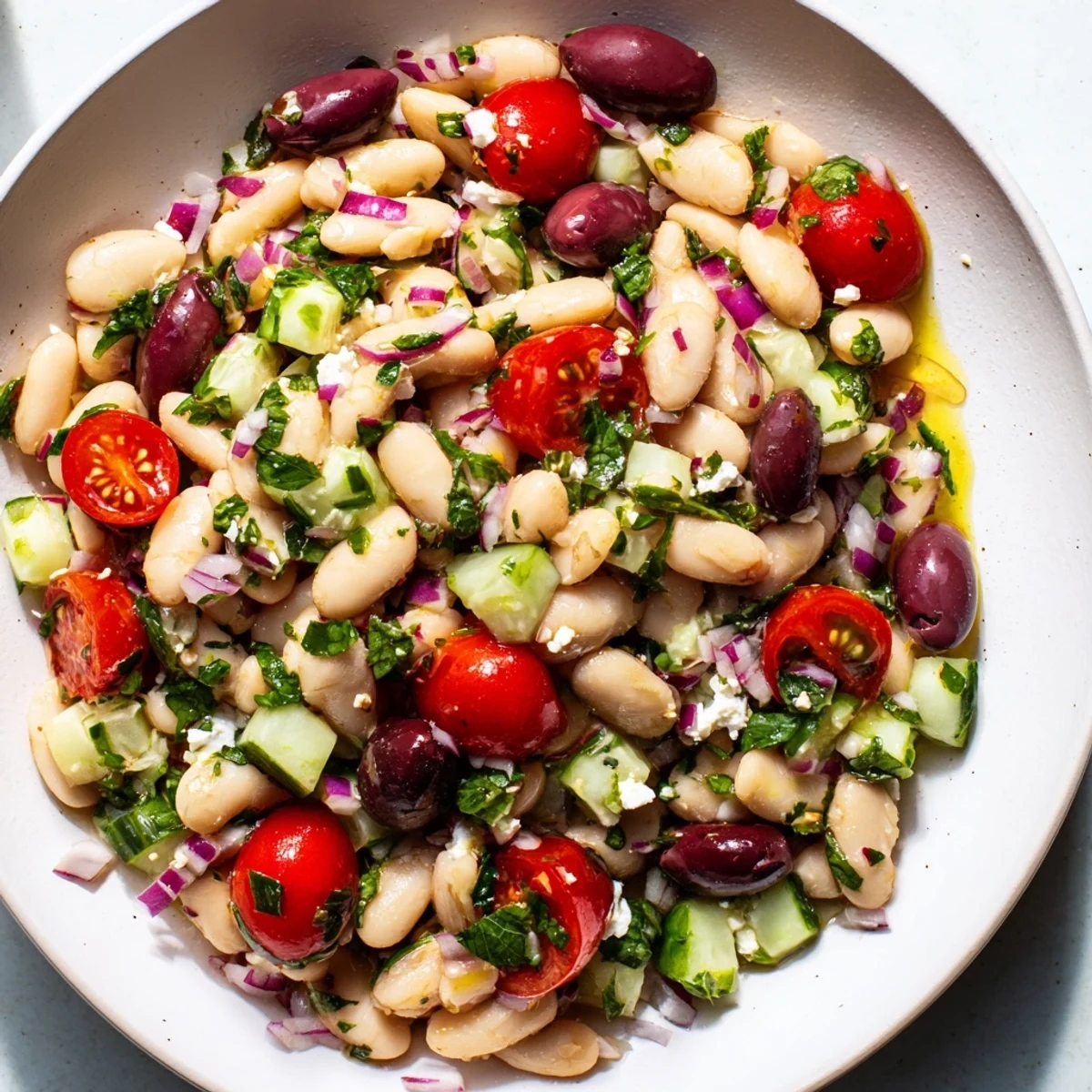 Vibrant white bean salad bursting with fresh flavors, tomatoes, and herbs, drizzled with olive oil.