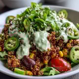 A hearty vegan bowl featuring spiced lentil-quinoa taco meat, creamy avocado lime crema, and colorful fresh toppings.  
