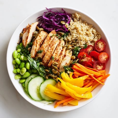 Colorful healthy meal-prep bowls with quinoa, chicken, and fresh vegetables arranged beautifully.  