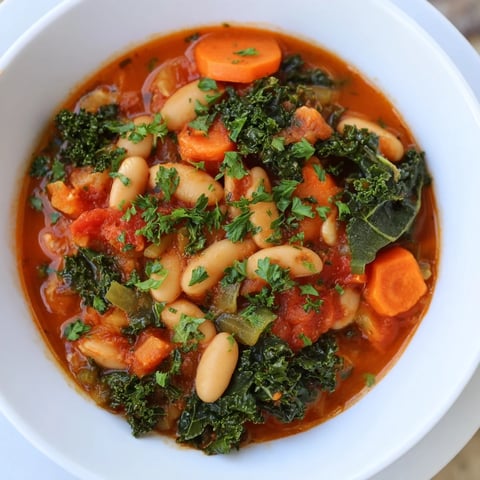 A steaming bowl of Italian Bean & Kale Stew, showcasing rustic textures and vibrant green kale.