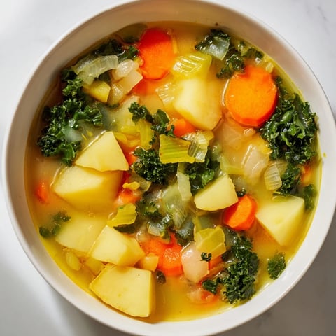Creamy Vegetarian Potato-Kale Soup, steaming, garnished with fresh herbs, ready to warm you up.