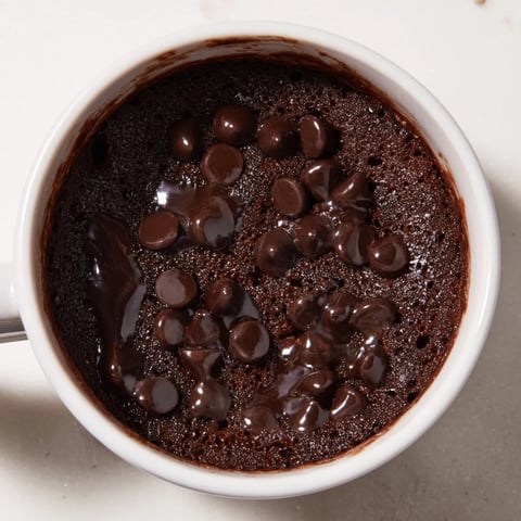 Steaming-hot microwaved mug cake, a quick dessert with chocolate chips, ready to eat now.