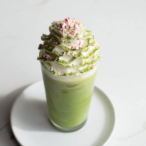 Sugar-Free White Chocolate Candy Cane Iced Matcha layered with whipped cream and crushed candy canes, a delightful treat.