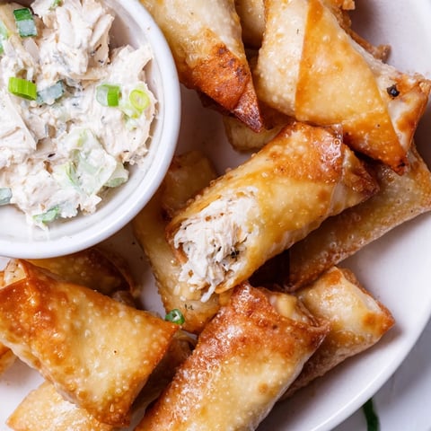 Golden brown air fryer lumpia chips alongside a creamy chicken cream cheese dip, ready to enjoy.