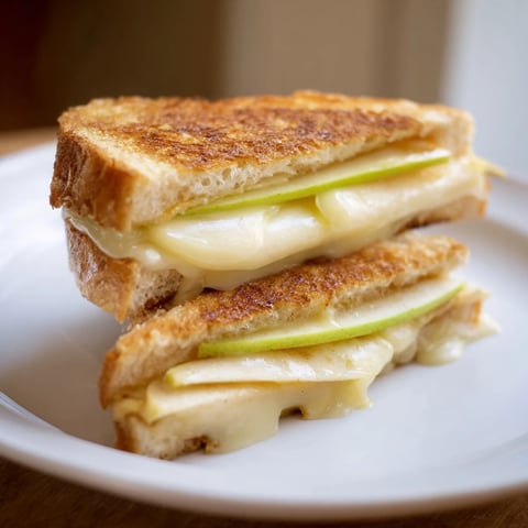 Golden, cheesy Brie and Apple Grilled Cheese sandwich, a gourmet delight with melted cheese and apple.