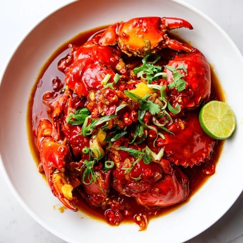 Steaming Singaporean chili crab, its vibrant red sauce clinging to succulent crab pieces ready to enjoy.