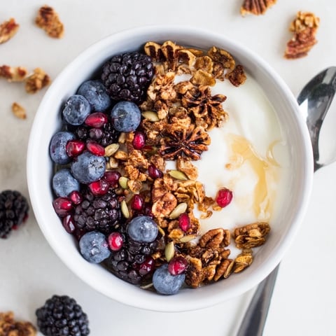 Creamy probiotic yogurt topped with jewel-toned winter berries and a fragrant, spiced crunch for a nourishing breakfast.