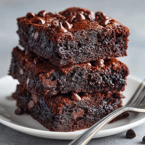 Moist chocolate avocado brownies sliced in squares, topped with melted dark chocolate chips.