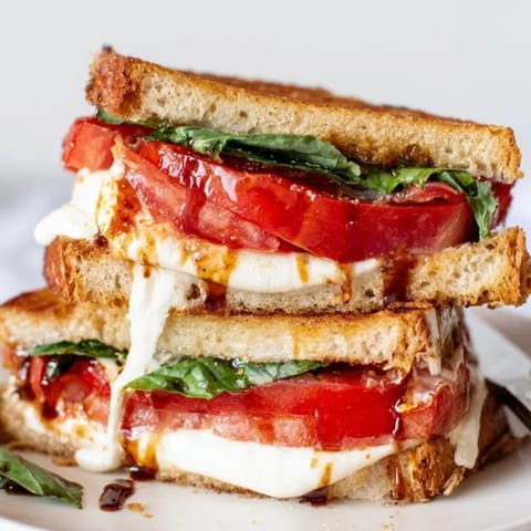 Buttery Caprese Grilled Cheese recipe, oozing cheese between crispy sourdough, basil visible.