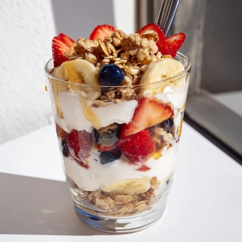 Tasteful homemade Yogurt Parfait with layered fruit, granola, and honey for breakfast.