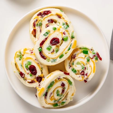 Colorful tortilla rolls filled with tangy cranberries and spicy jalapeños, perfect for entertaining.  