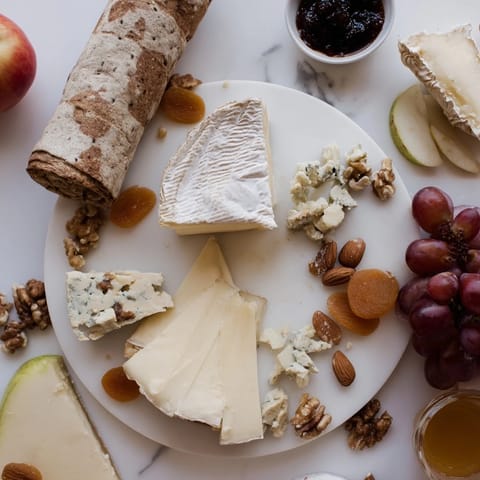 A beautifully arranged Cheese Platter Cœur Passion, overflowing with French cheeses and fresh fruit.