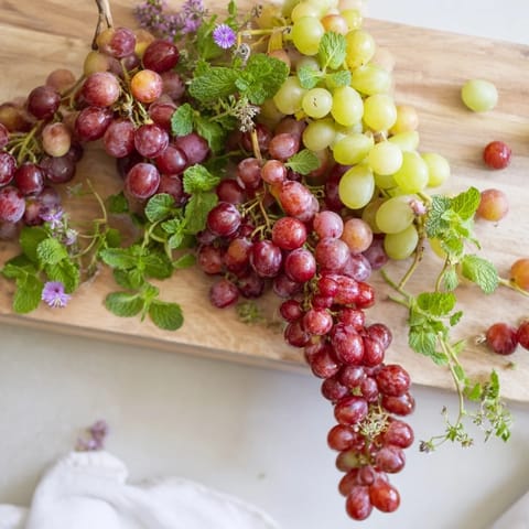 Juicy red and green grapes cascade over the serving board, a fresh appetizer presentation for easy entertaining.
