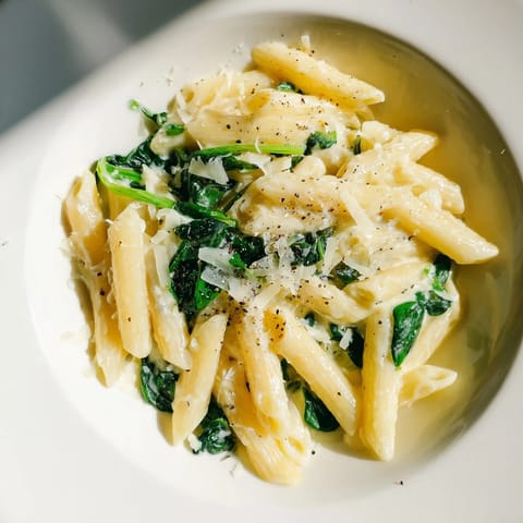 A close-up of finished Creamy Spinach Pasta, creamy sauce glistening over the penne pasta.