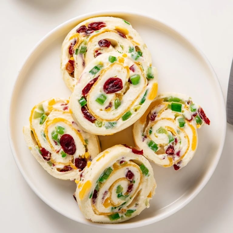 Colorful tortilla rolls filled with tangy cranberries and spicy jalapeños, perfect for entertaining.  