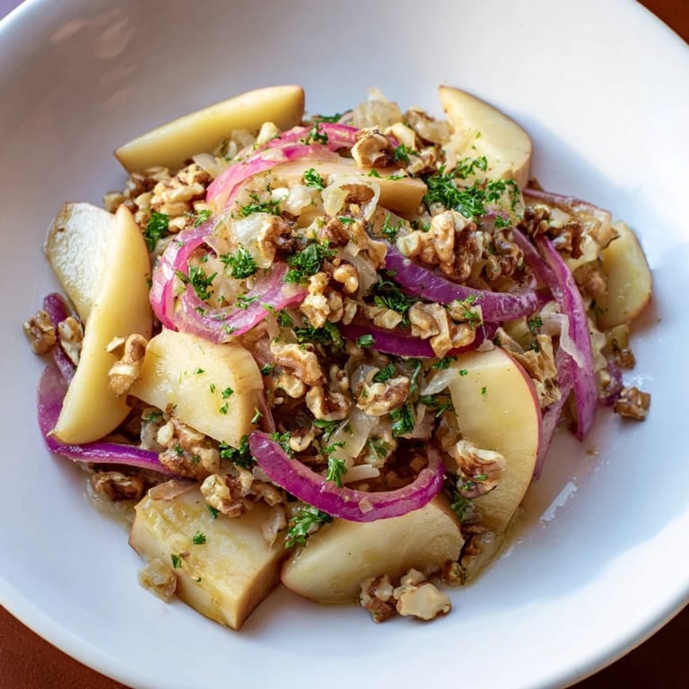 A vibrant Warm Apple and Sauerkraut Skillet Salad topped with nuts and herbs alongside grilled sausages.